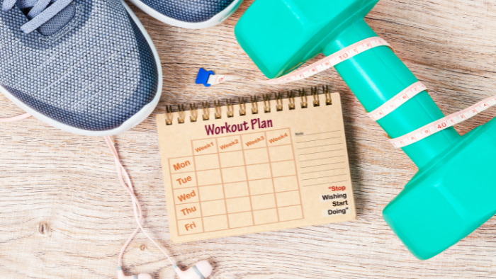 A Workout Plan Notebook With a Tape Measure and Pen